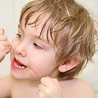 Young child flossing teeth