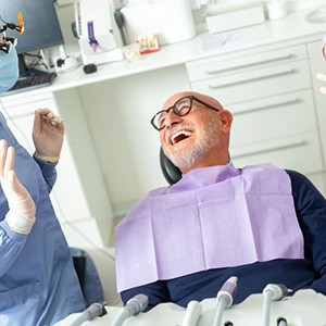 Happy dental patient laughing with his care team