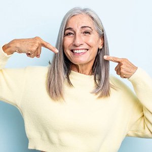 Happy, mature woman pointing at her teeth