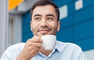 Man holding a white coffee cup outdoors