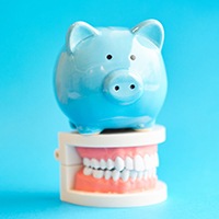 A piggy bank and teeth that show the cost of cosmetic dentistry in Huntington Beach is an investment