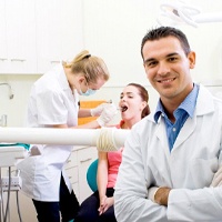 Two dentists helping a patient.