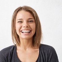 young woman with a dental bridge in Huntington Beach, CA smiling