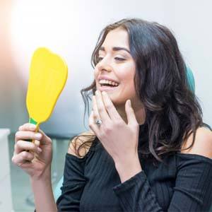 dental patient admiring her new smile after getting dental crowns in Huntington Beach 