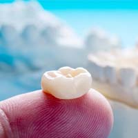 dentist in Huntington Beach holding a dental crown on their finger