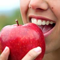 close-up of a person biting into a red apple