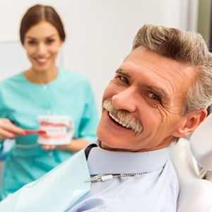 older man in dental chair learning about dentures in Huntington Beach 