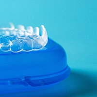Close-up of clear aligner resting on blue storage case