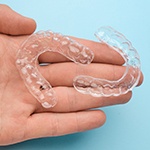 person holding two clear aligners