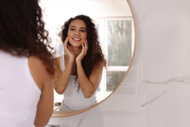 Woman looking at her smile in a small mirror