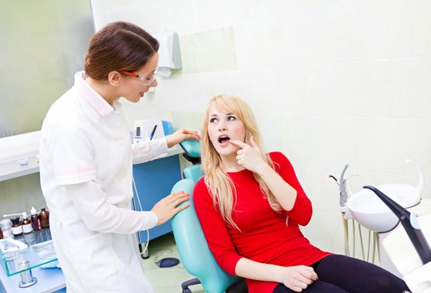 Man in dental chair touching jaw in pain