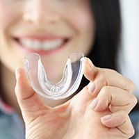 young woman holding up a clear mouthguard