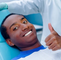 Man with thumb’s up in dentist’s chair