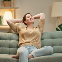 Woman relaxing on green couch with hands on her head