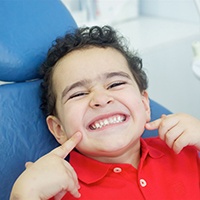 Little boy in dental chair pointing to his teeth