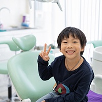 Little boy in dental chair giving a peace sign