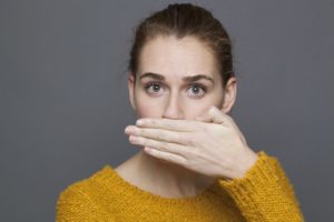 woman covering her mouth embarrassed