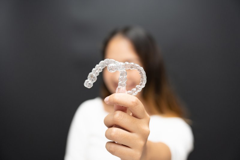 young woman holding up two clear aligners