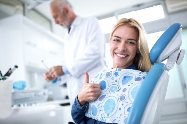 Woman at the dentist's office giving a thumb's up.