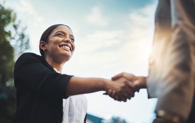 Someone smiling and shaking a hand