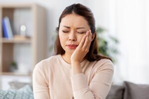Woman clutching her jaw in pain. 