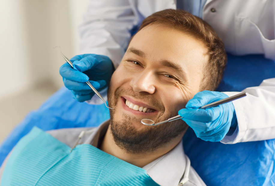 Man smiling in dentist chair while dentist holds instruments over him