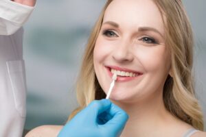 Dentist holding veneer up to smiling patient. 